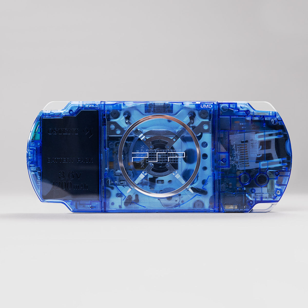 Back view of a blue transparent PSP console with visible UMD drive and OSTENT 3.6V 1200mAh battery pack, housed in a custom clear shell