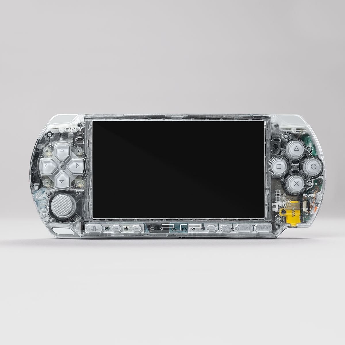 Front view of a Sony PSP console with a fully transparent clear shell and grey control buttons, showing internal components and clean mod finish