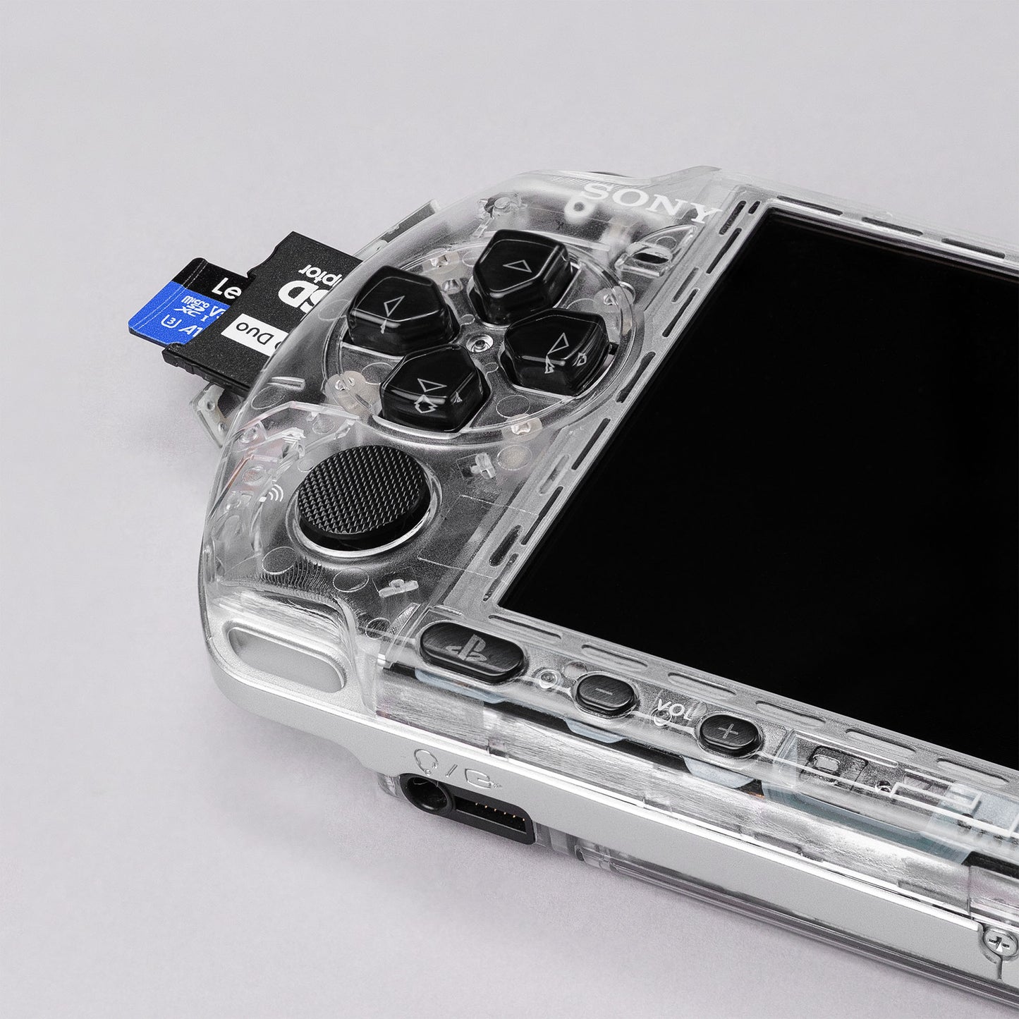 Front view of a Sony PSP with a custom transparent shell, showing memory stick duo inserted, directional buttons, and control layout