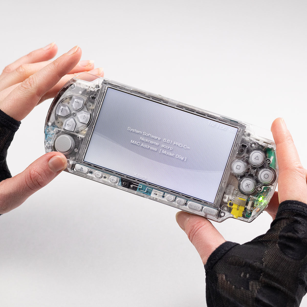 Transparent clear PSP with grey buttons running firmware 6.61 PRO-C, shown in use with system info on screen and held in gloved hands