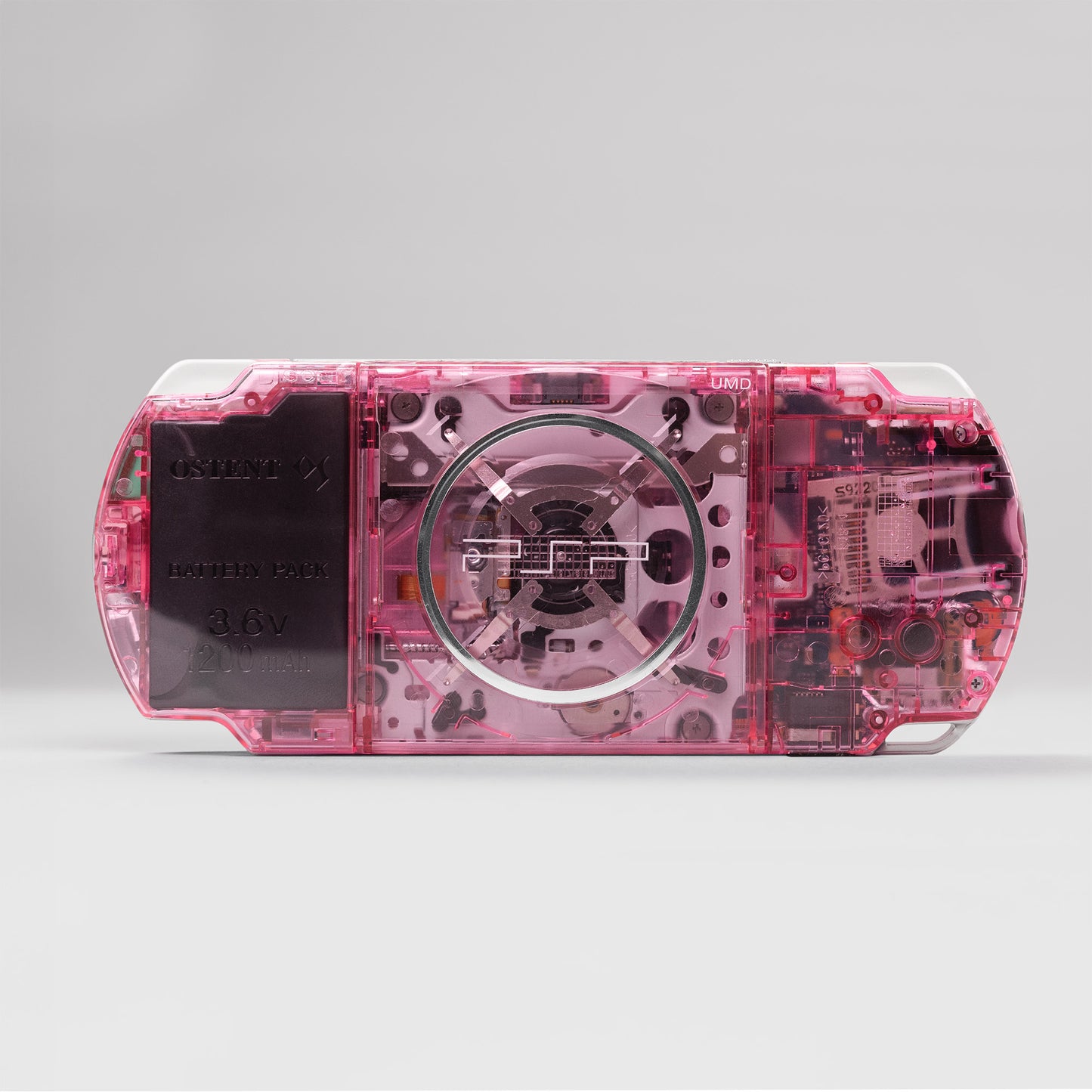 Rear view of a custom pink Sony PSP with transparent back shell, showing UMD drive and OSTENT 3.6V 2200mAh battery pack