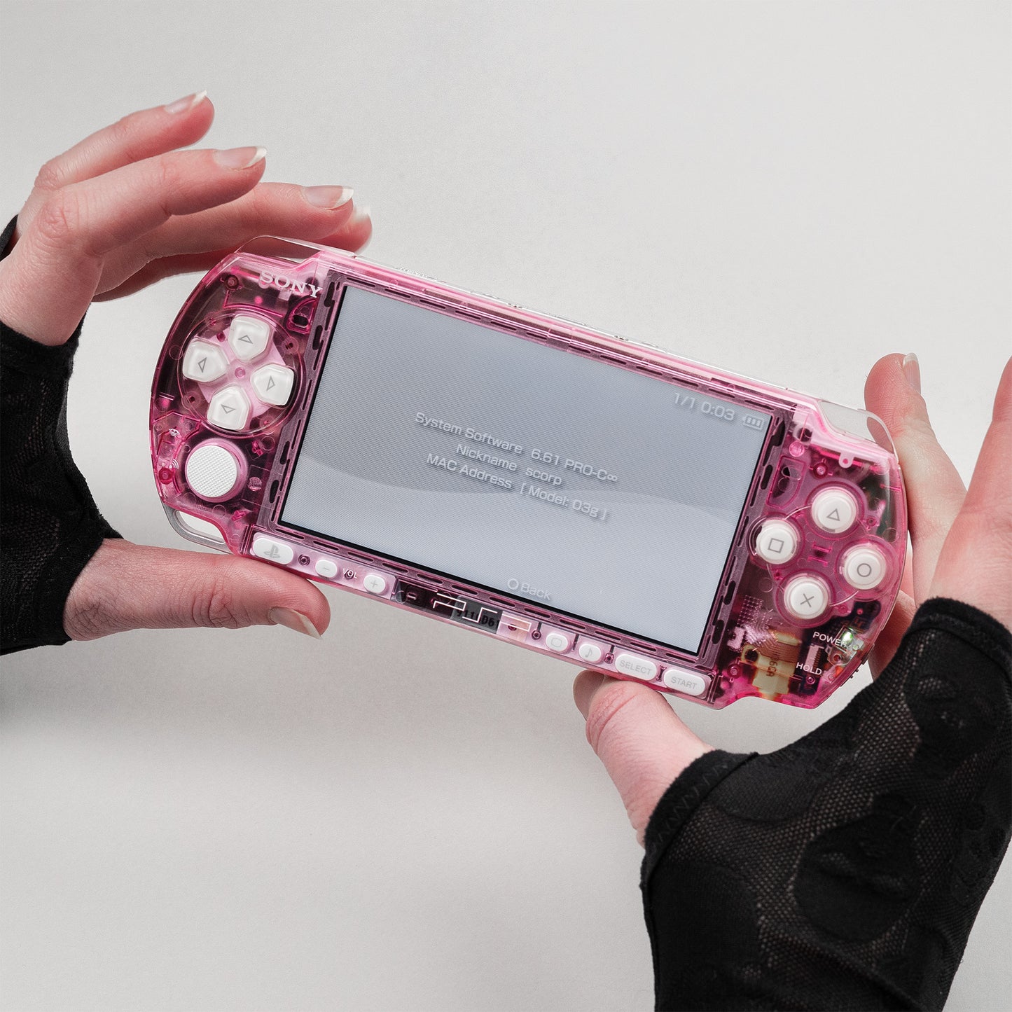 Modded pink Sony PSP with transparent clear shell and white buttons, running system firmware 6.61 PRO-C, held in gloved hands