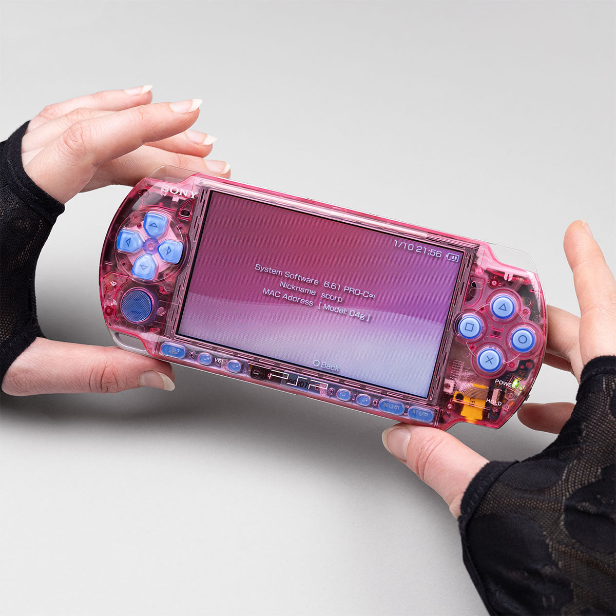 Custom pink transparent PSP 3000 handheld console with blue buttons, shown in hands while running custom firmware