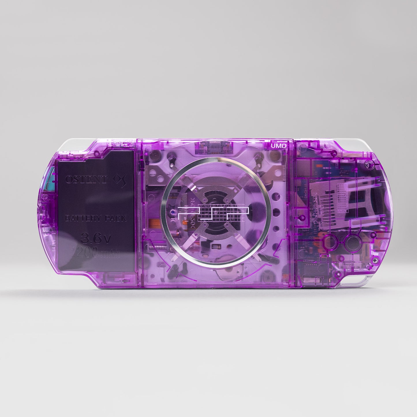 Back view of a custom Sony PSP with a purple transparent shell, featuring visible UMD drive components and an OSTENT 3.6V 1200mAh battery pack