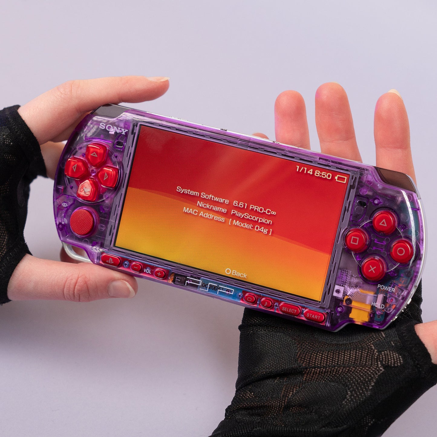 Modded Sony PSP with a purple transparent shell and red buttons, running firmware 6.61 PRO-C, held in hands with screen displaying system info