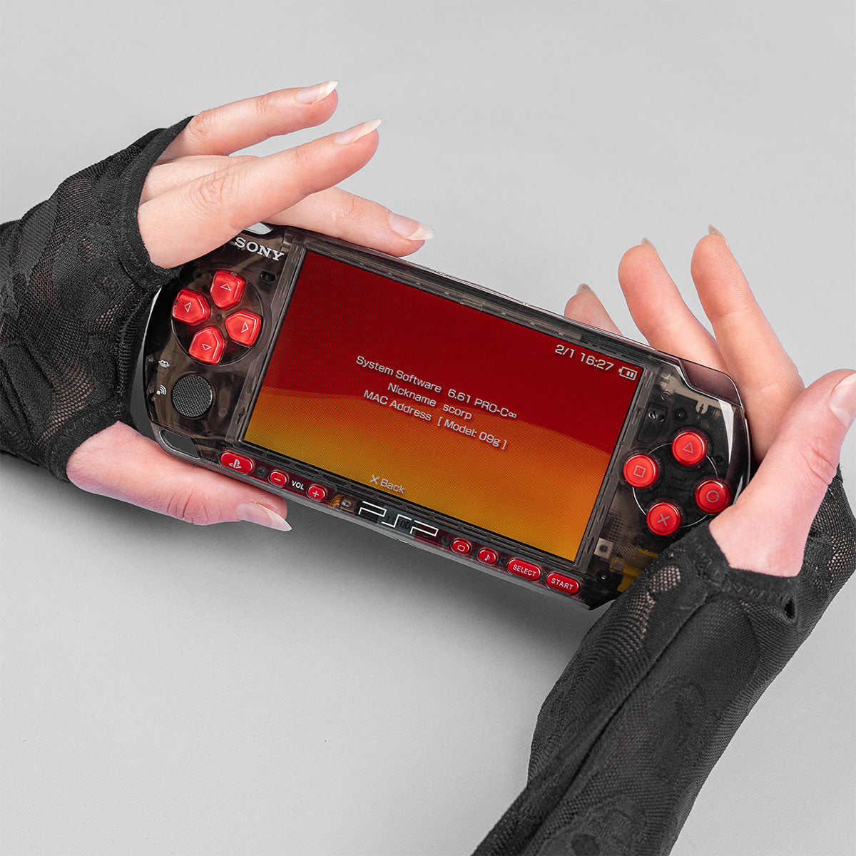 Smoke black transparent PSP with red buttons running firmware 6.61 PRO-C, held in gloved hands with red-orange system info screen displayed