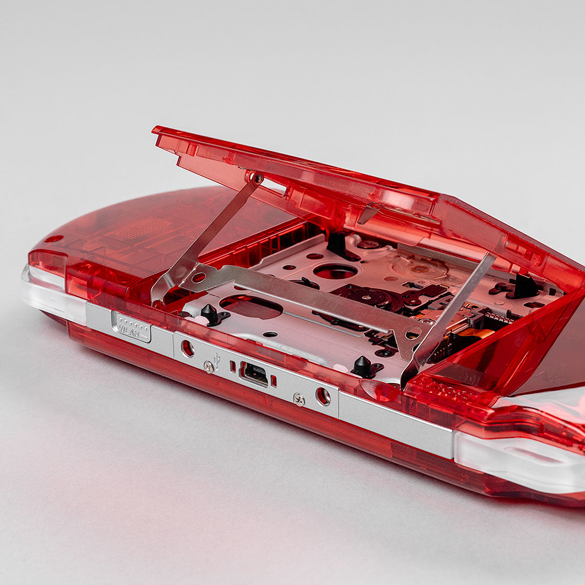 Custom transparent red Sony PSP 3000 with open UMD disc drive tray showing internal housing and components