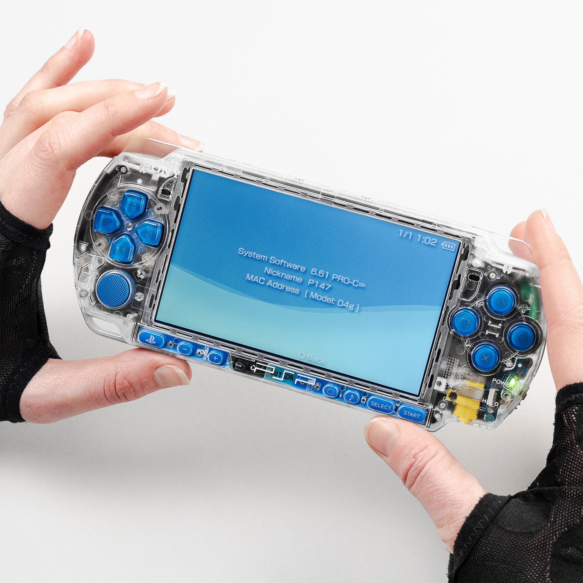 Transparent clear PSP console with blue buttons running firmware 6.61 PRO-C, held in hands with screen displaying system information