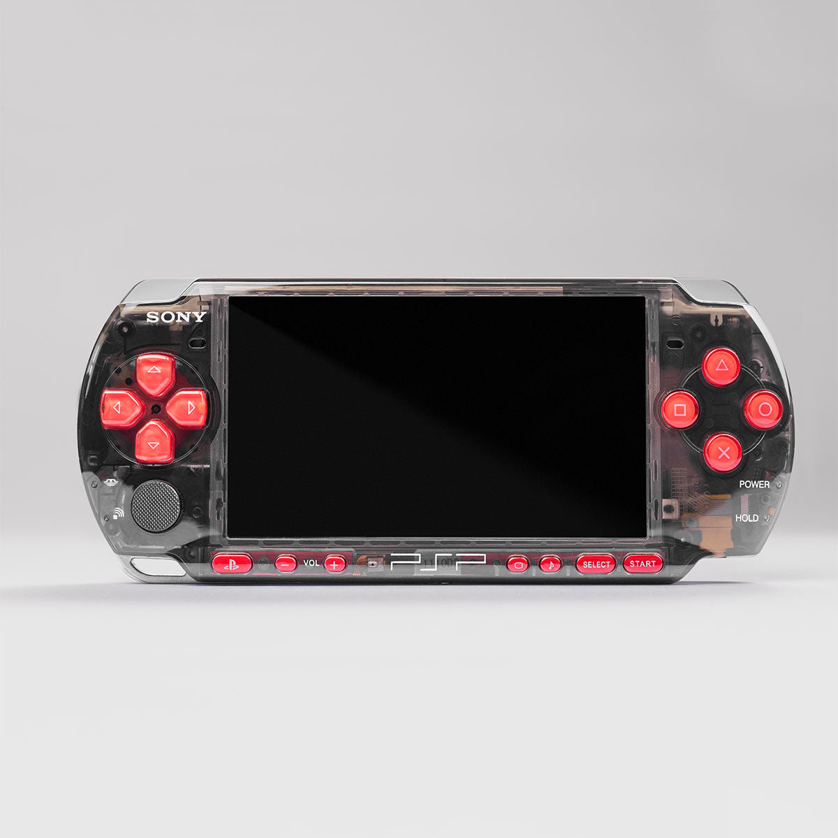 Front view of a custom Sony PSP with a transparent smoke black shell and bright red buttons, showcasing a modded handheld gaming console