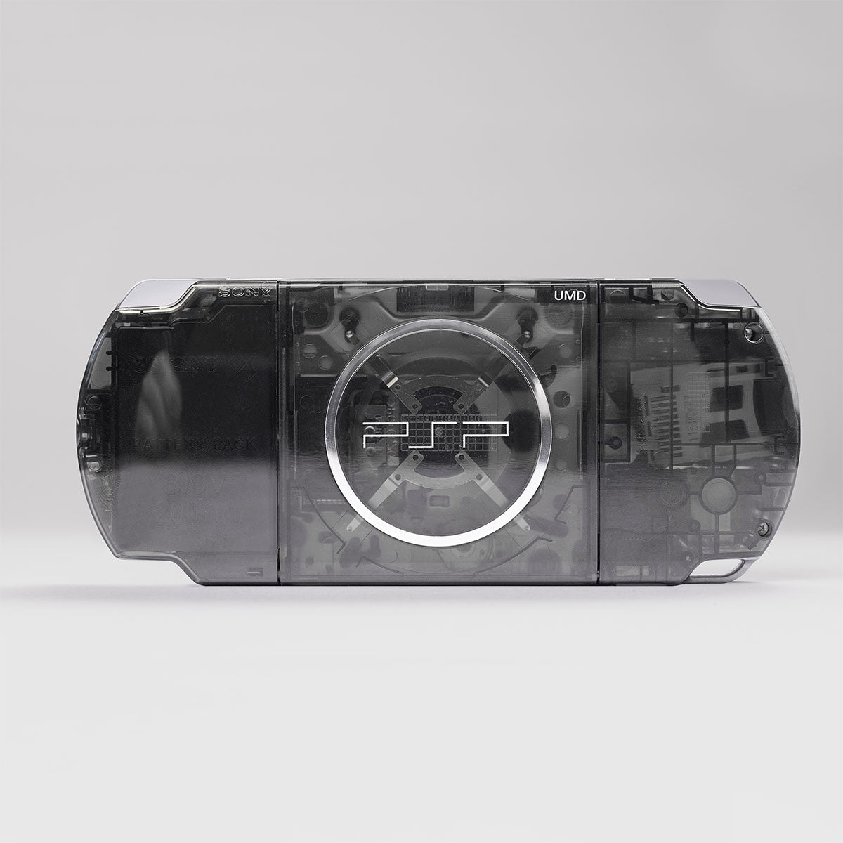 Back view of a custom PSP with a smoke black transparent shell showing the UMD drive and internal components through the clear casing