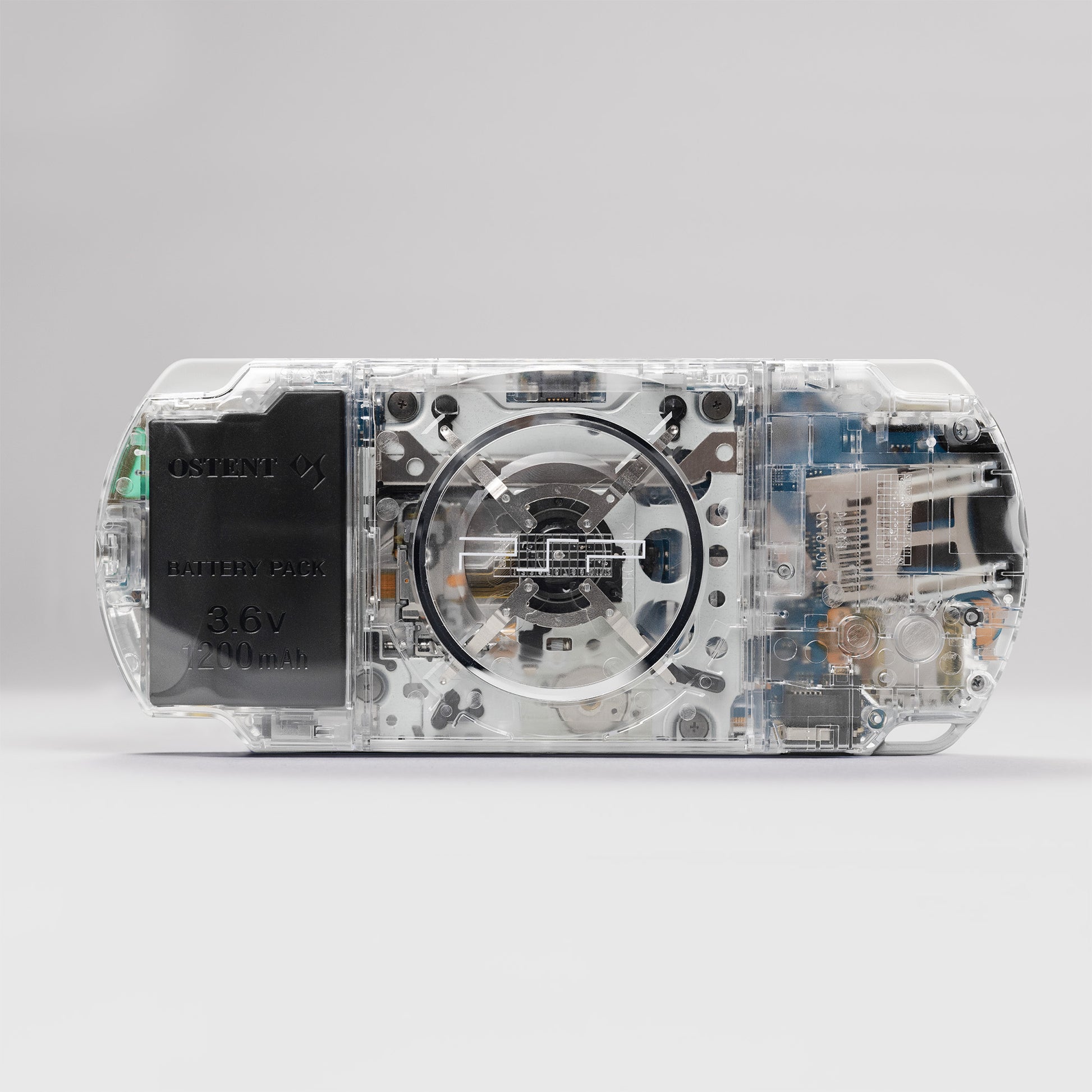 Back view of a Sony PSP with a custom transparent clear shell and exposed internal components, featuring an OSTENT 3.6v 2200mAh battery pack